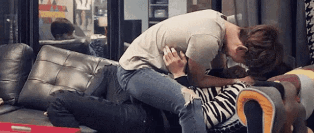 a man and a woman are laying on a couch kissing .