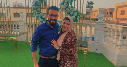 a man and woman are posing for a picture in front of a fence