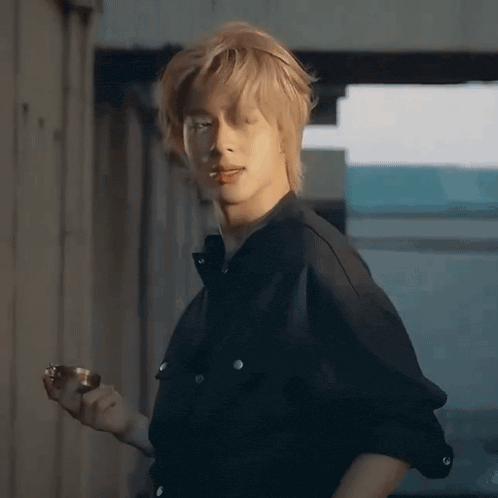 a young man in a black shirt is smoking a cigarette and holding a ring .