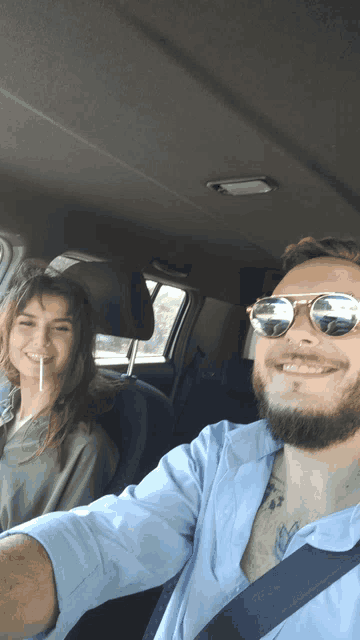 a man wearing sunglasses is driving a car next to a woman