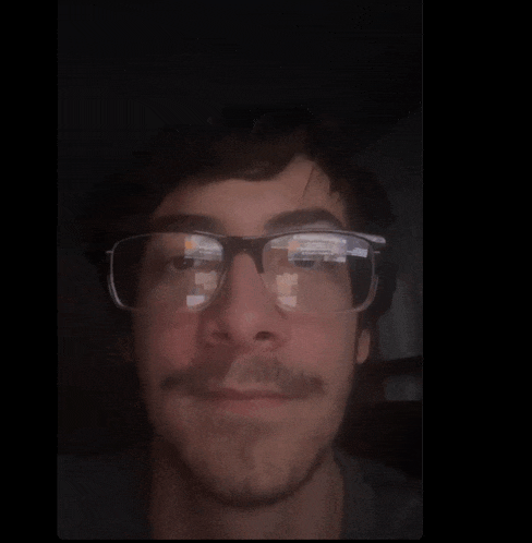 a man with glasses and a beard is looking at the camera