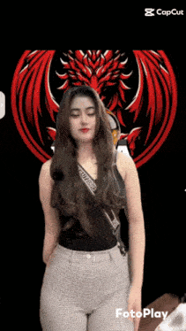 a woman in a black tank top and plaid pants is dancing in front of a red dragon logo