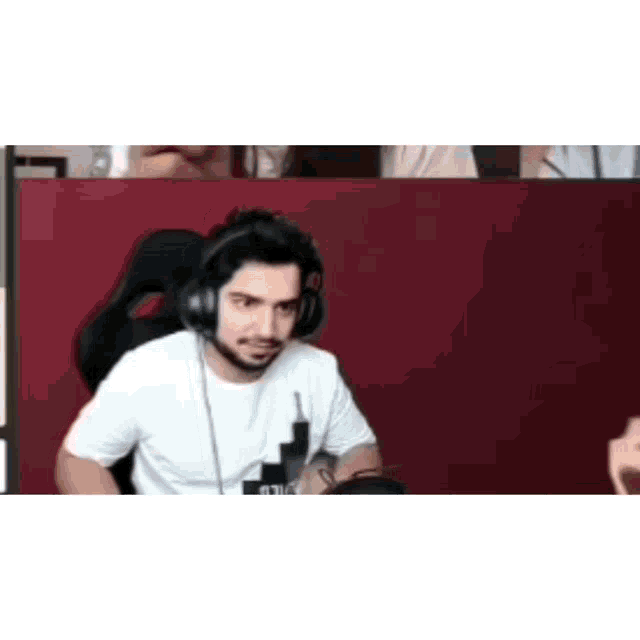 a man wearing headphones is giving the middle finger while sitting in front of a computer screen .