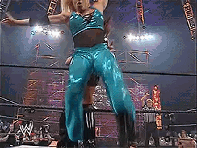 a woman in blue pants is standing in a wrestling ring