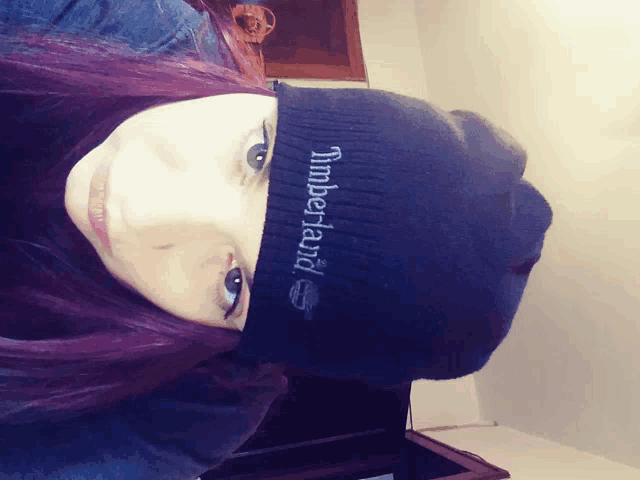 a woman is wearing a black timberland beanie