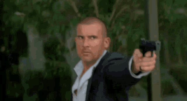 a man in a suit is pointing a gun at something .