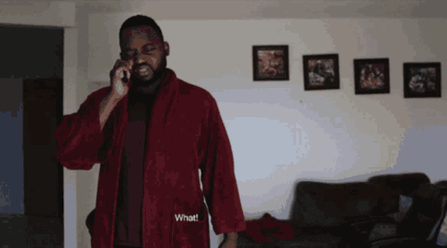 a man in a red robe talking on a cell phone with the words what written on his robe