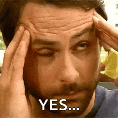 a man with a beard is holding his head with his hands and says yes .
