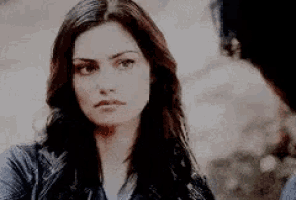 a woman with long dark hair is looking at a man .