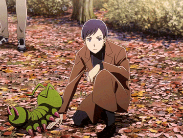 a man in a suit is kneeling next to a green caterpillar