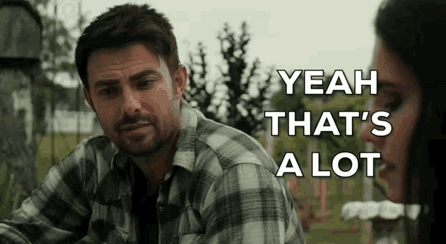 a man in a plaid shirt is sitting next to a woman in a cemetery .