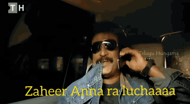 a man wearing sunglasses is talking on a cell phone and the words zaheer anna ra luchaaaa are visible