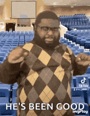 a man wearing glasses and a plaid sweater says he 's been good in front of an auditorium .