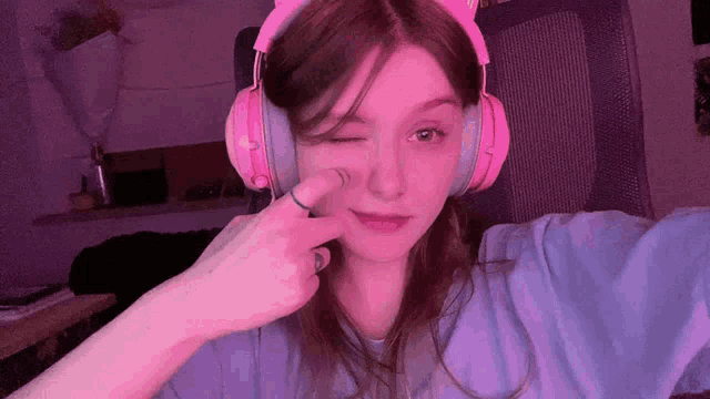 a girl wearing pink headphones with cat ears winks