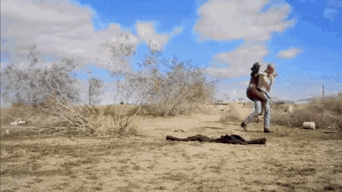 a man and a woman are running in the desert .