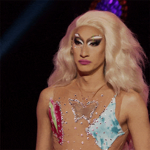 a drag queen with blonde hair is wearing a colorful outfit