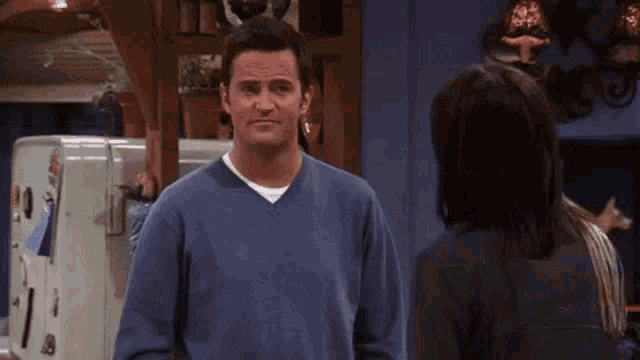 a man in a blue sweater stands next to a woman