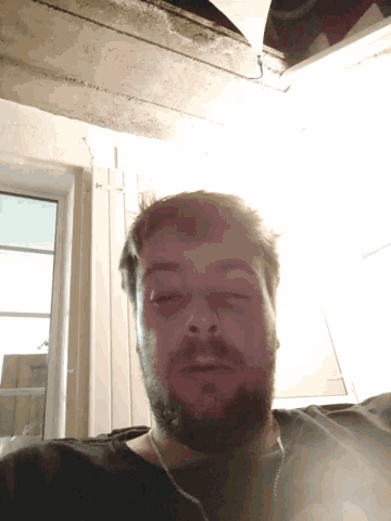 a man with a beard is looking down at the camera