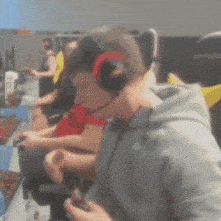 a man wearing headphones is playing a video game in a room with other people