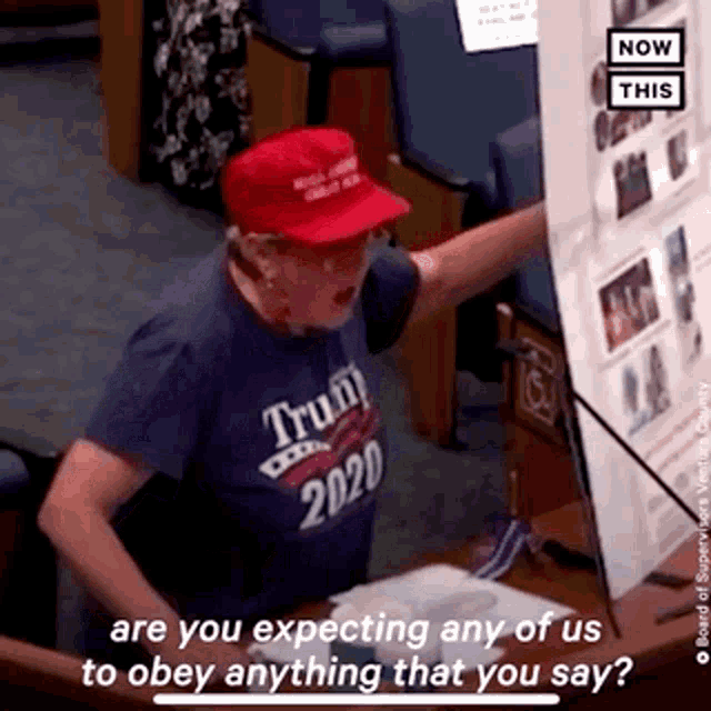 a man wearing a trump 2020 shirt and a red hat
