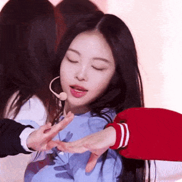 a girl with long black hair is wearing a red jacket and a microphone .