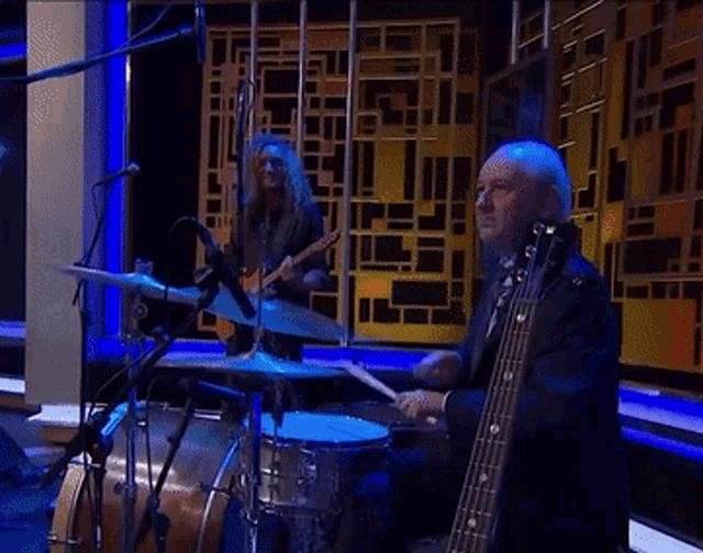 a man playing drums and another man playing guitar