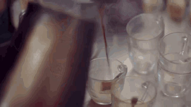 a close up of a person pouring a drink into a cup