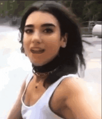 a woman is wearing a white tank top and a black choker .