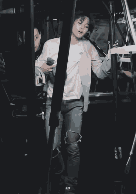 a man in a white shirt and ripped jeans is standing next to a man in a black shirt