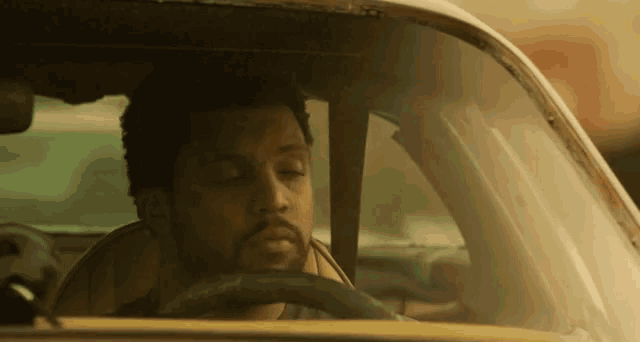 a man is sitting in the driver 's seat of a car with his eyes closed .
