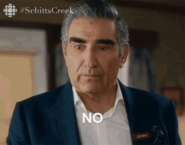a man in a suit says no in front of a #schittscreek logo