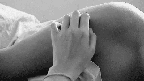 a black and white photo of a person touching another person 's foot .