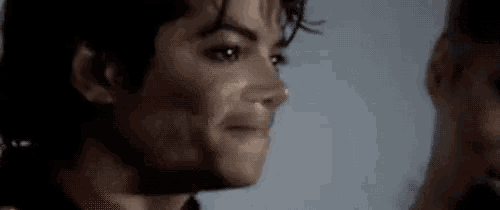 a close up of a man 's face with a ponytail and a smile on his face .