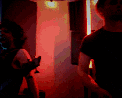 a man in a black shirt is standing in front of a red light