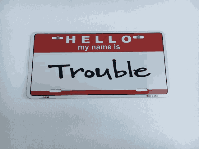 a red and white hello my name is trouble name tag