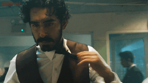 a man with a beard is adjusting his tie with the words monkey man visible in the background
