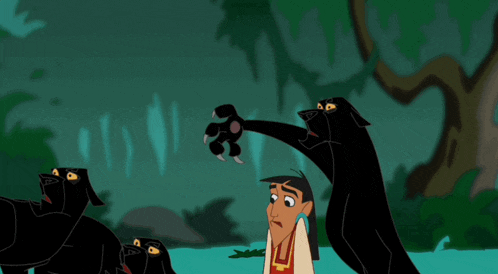 a man in a red shirt stands in front of a group of black dogs with their mouths open