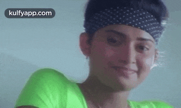 a close up of a woman wearing a green shirt and a headband .