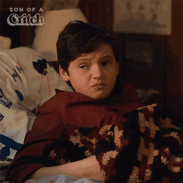 a young boy is laying in bed with a blanket and the words son of a grifch behind him