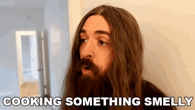 a man with long hair and a beard is saying something smelly