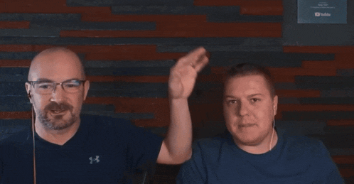 two men are smiling in front of a wall with a youtube sign on it