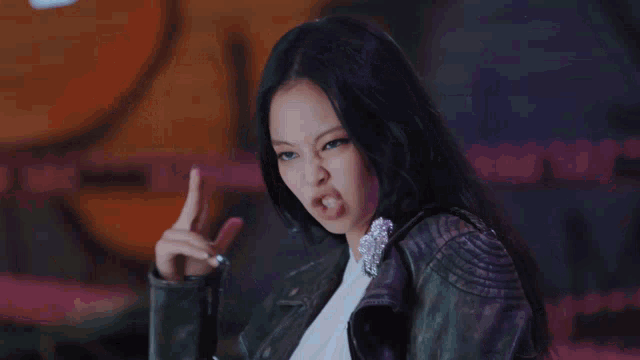 a woman wearing a black leather jacket and a white top is dancing