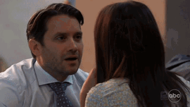 a man in a suit and tie is talking to a woman with the abc logo in the corner