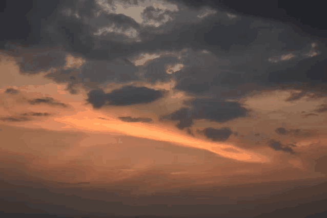 a dark cloudy sky with a sunset in the distance