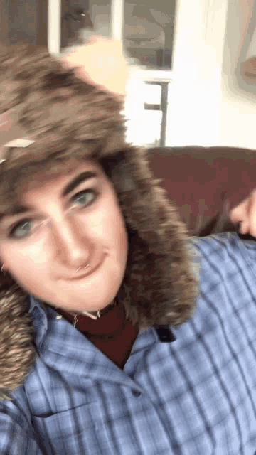 a man wearing a fur hat and a plaid shirt