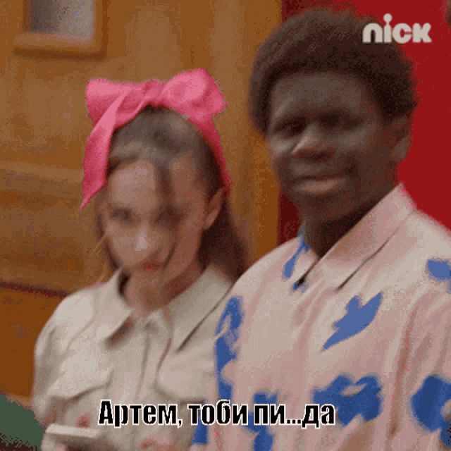 a girl with a pink bow on her head is standing next to a man with a nick logo