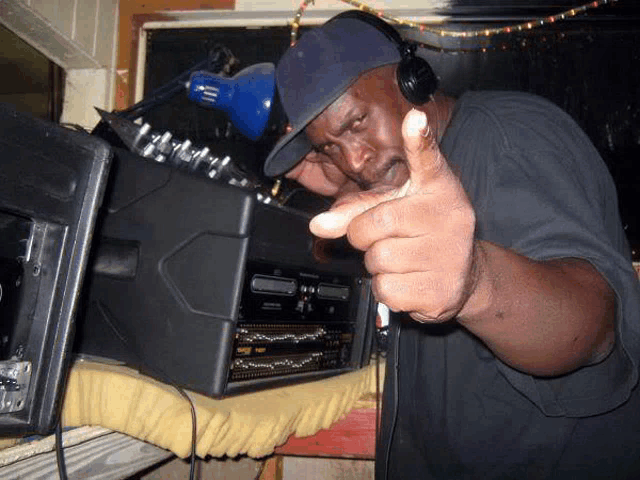 a man wearing headphones and a hat is pointing at something