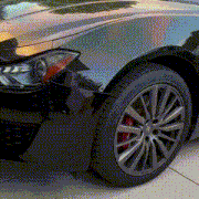 a black car with red brake calipers is parked on the sidewalk
