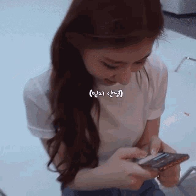 a woman in a white shirt is holding a cell phone in her hand .