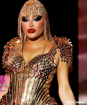 a woman is wearing a gold dress with spikes on the shoulders and a gold headpiece